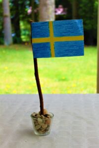 Schweden-Flagge auf einem Stock in einem Glas mit Steinen, Midsommar-Dekoration